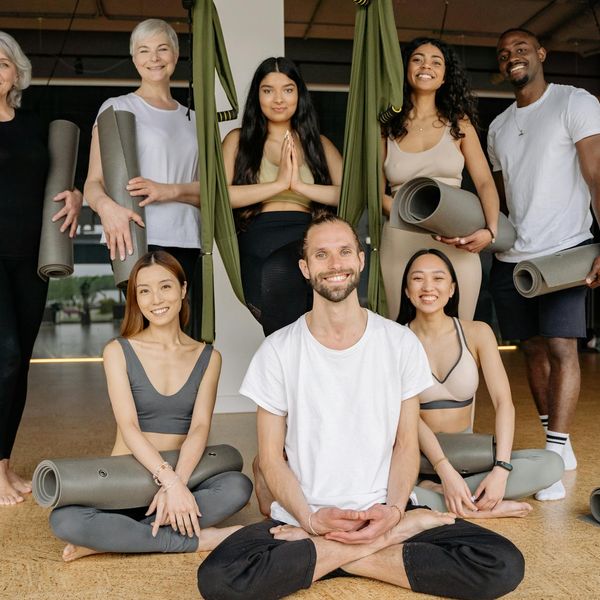 Diverse group of people smiling and preparing for a yoga class.