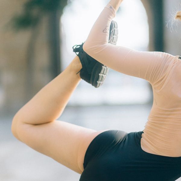 Person stretching in a sunlit outdoor yoga pose, feeling energized.